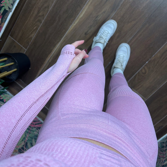 woman wearing pink seamless sporty leggings and matching top with white sneakers standing on wooden floor