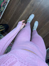 woman wearing pink seamless sporty leggings and matching top with white sneakers standing on wooden floor