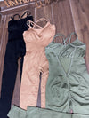 Three SPORT 03 sleeveless workout jumpsuits in black, beige, and olive green laid flat on wooden floor.