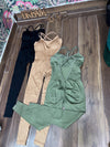 Three SPORT 03 women's one-piece athletic jumpsuits in black, beige, and olive green laid on wooden floor