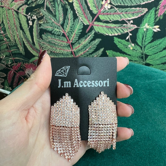 Rose gold chandelier earrings with multiple rows of sparkling rhinestones on a black J.m Accessori card