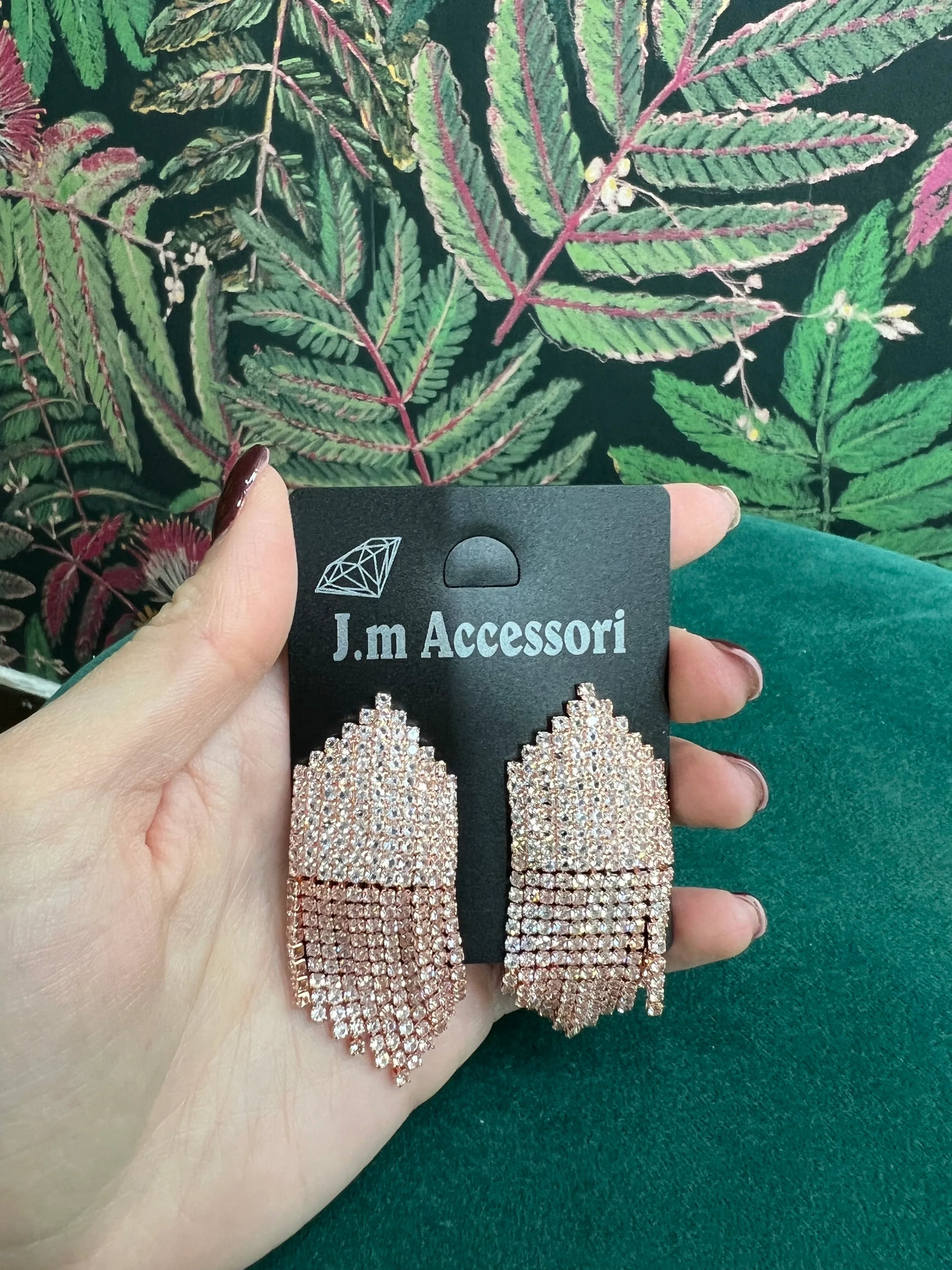 Rose gold chandelier earrings with multiple rows of sparkling rhinestones on a black J.m Accessori card