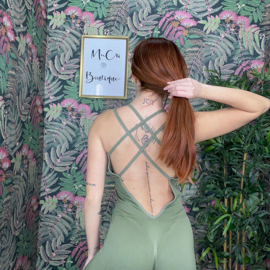 woman wearing green crisscross back SPORT 03 activewear against floral wallpaper in boutique setting