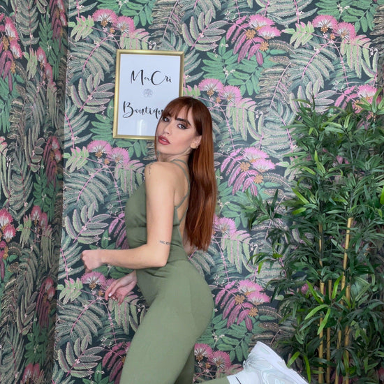 woman wearing olive green SPORT 03 activewear outfit posing against tropical floral wallpaper background